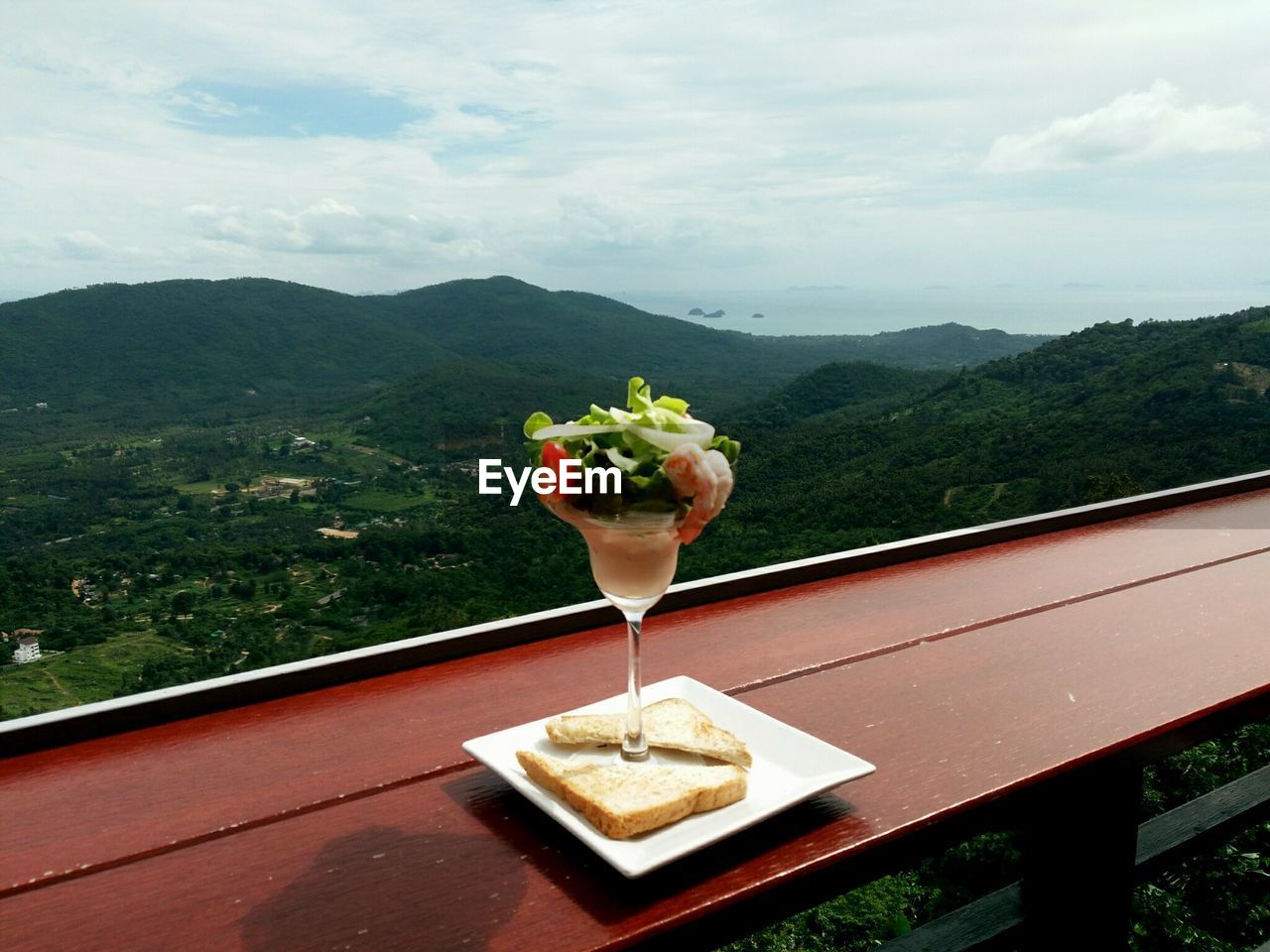 CLOSE-UP OF ICE CREAM ON TABLE AGAINST MOUNTAIN