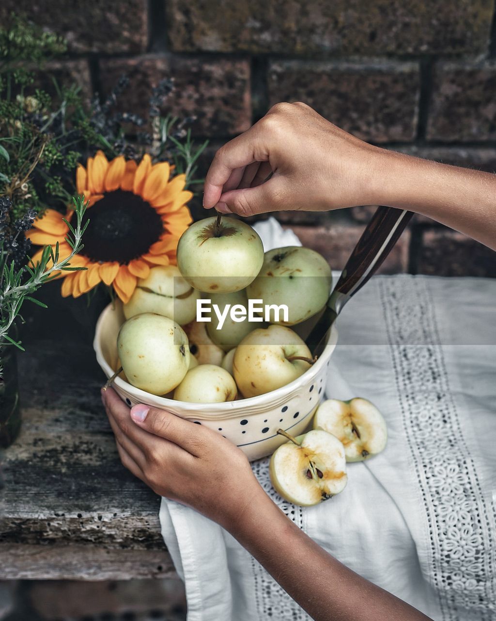 Cropped hands of woman arranging apples in bowl on table