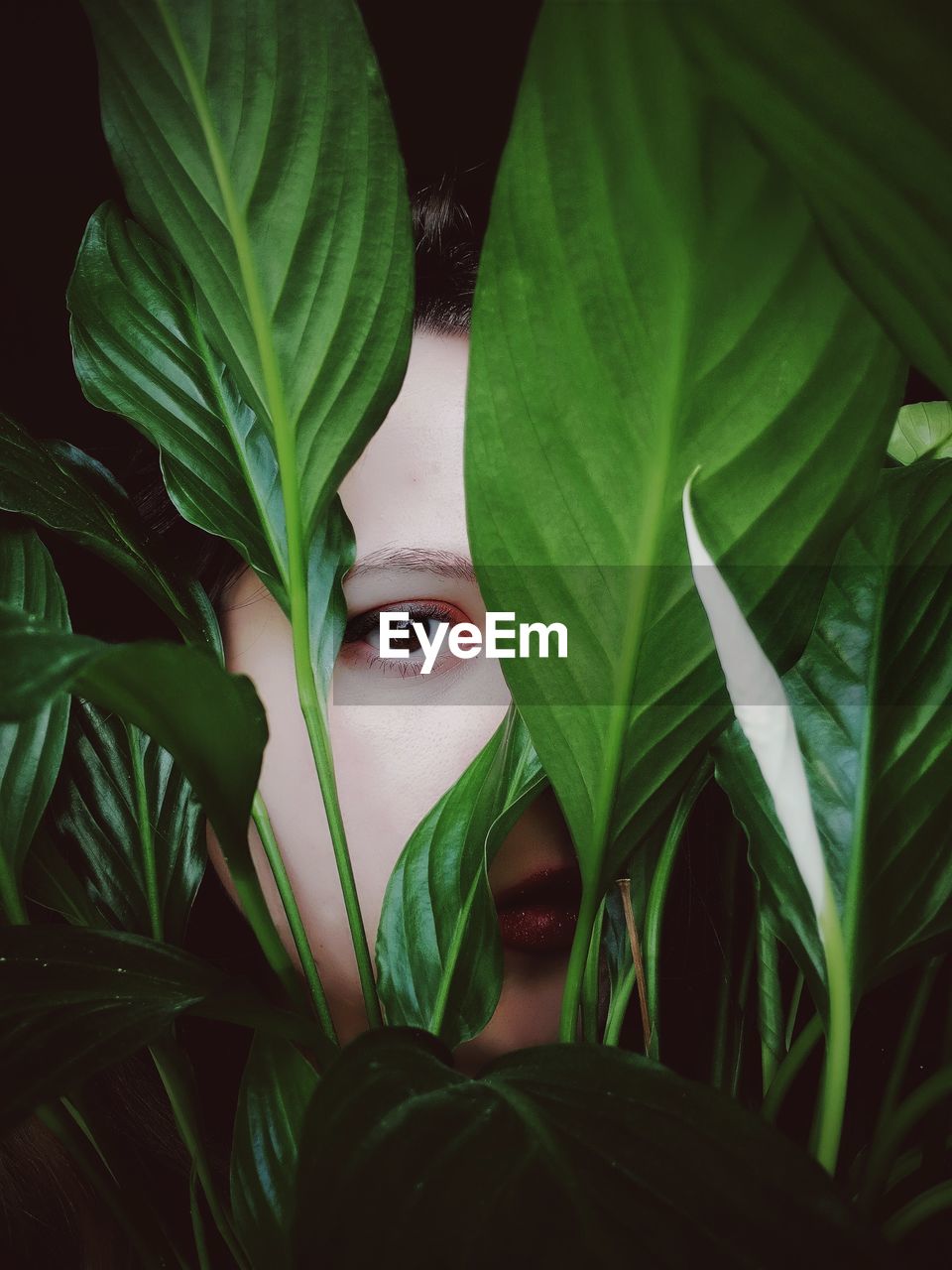 Close-up portrait of young woman seen through plants