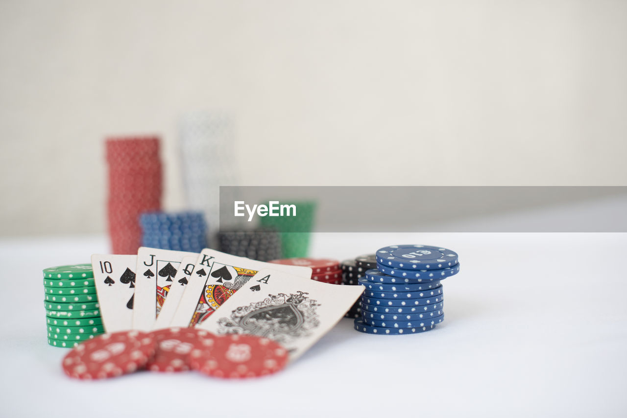 Close-up of cards and chip  on table against white background