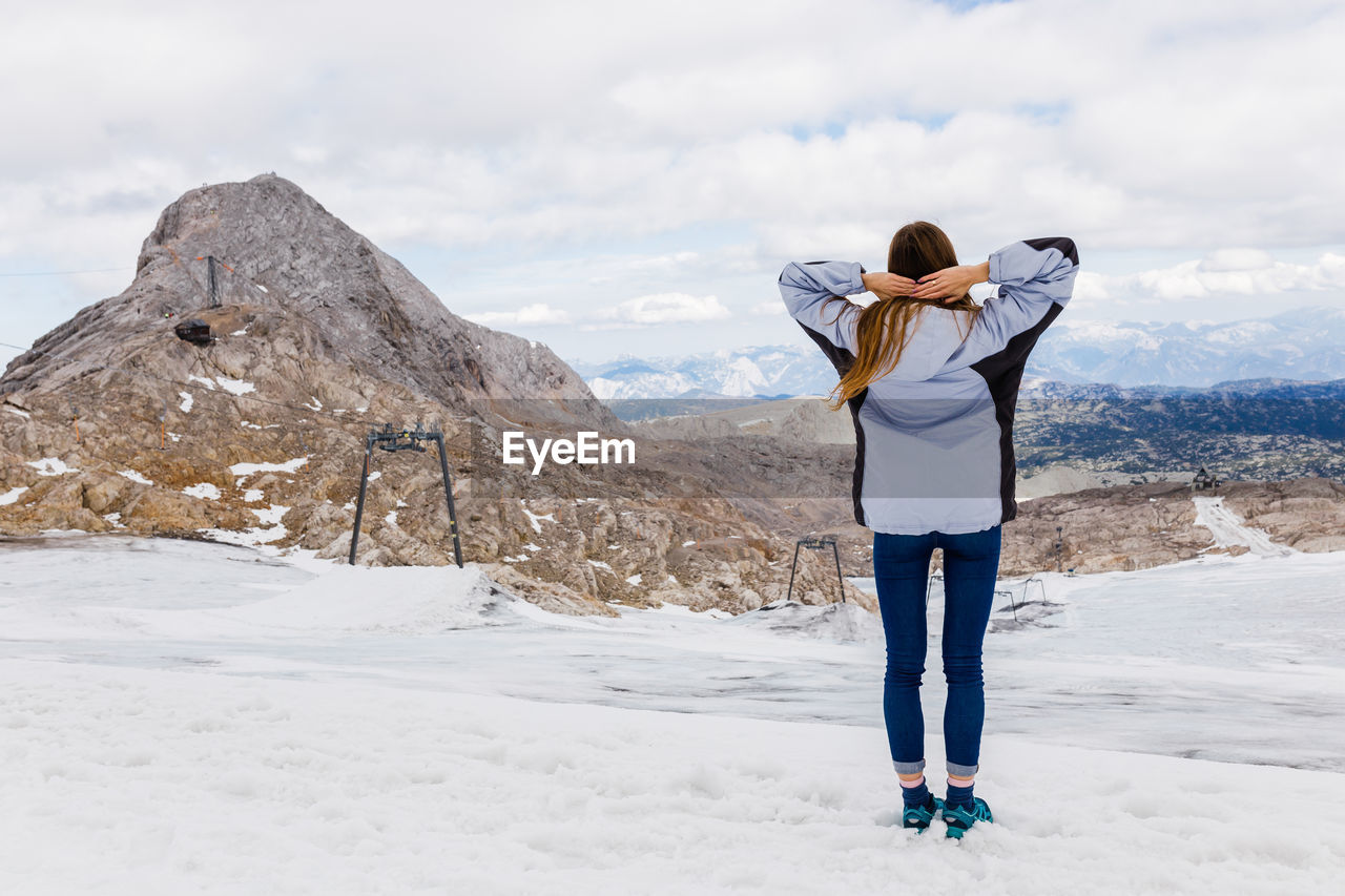 Young millennial girl enjoys the views of the alps standing on glacier