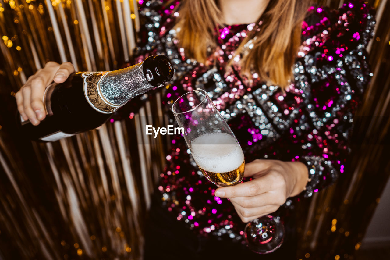 Midsection of woman pouring champagne in glass