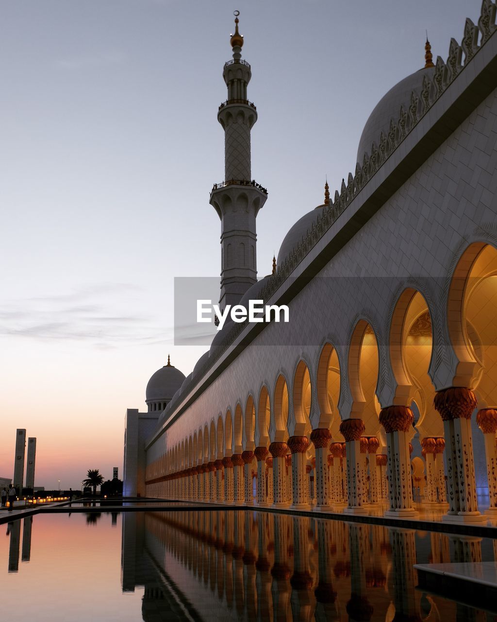 Sheikh zayed mosque with reflection in pond during sunset