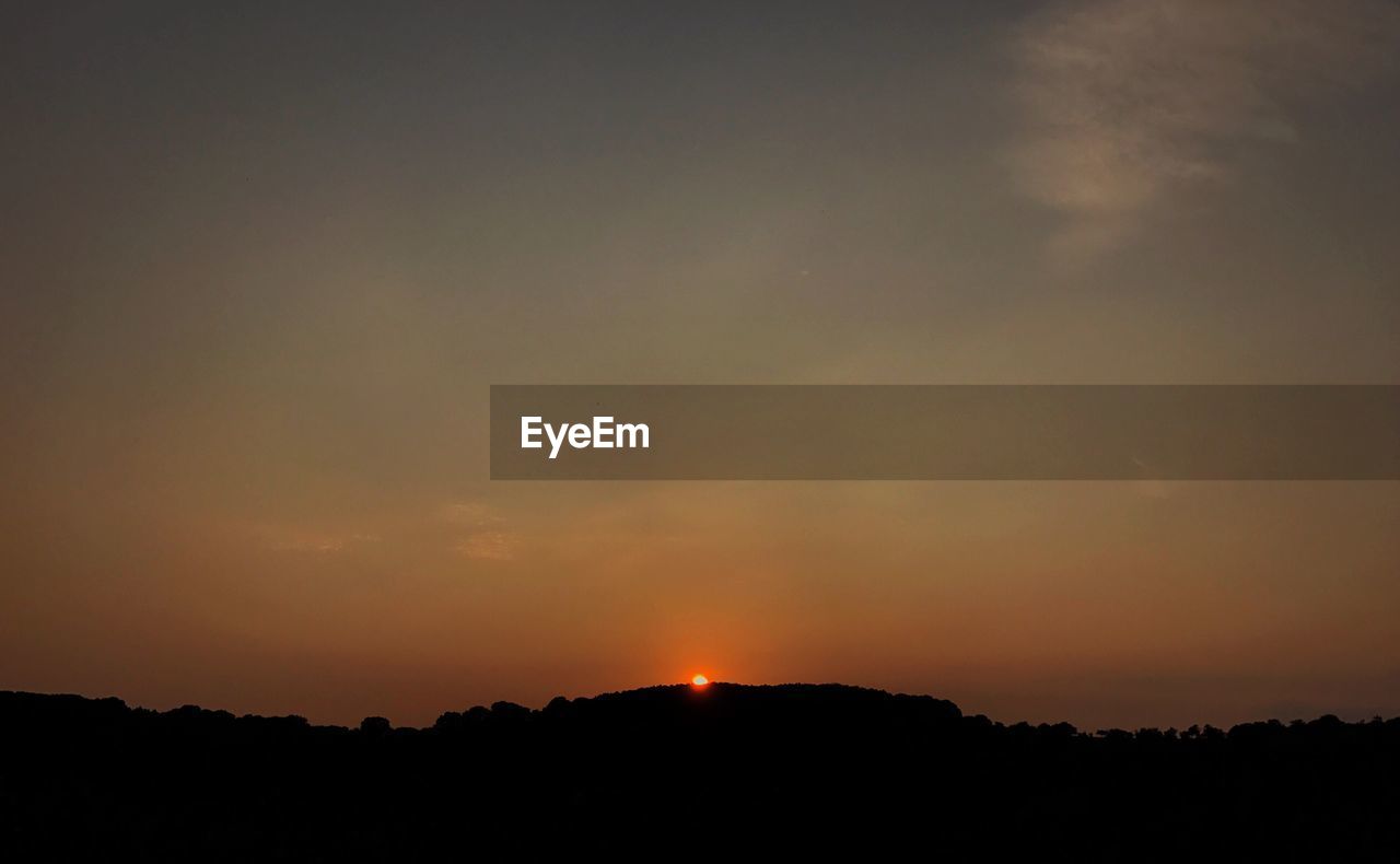 SCENIC VIEW OF SILHOUETTE FIELD AGAINST SKY DURING SUNSET