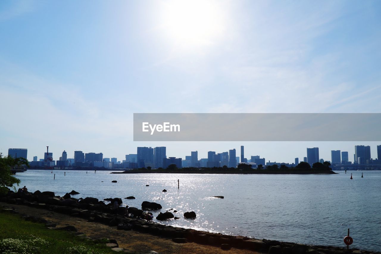 SEA BY BUILDINGS AGAINST SKY DURING SUNNY DAY