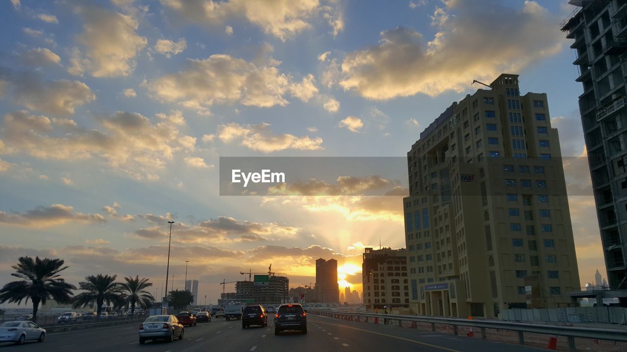 CARS ON ROAD IN CITY AGAINST SKY