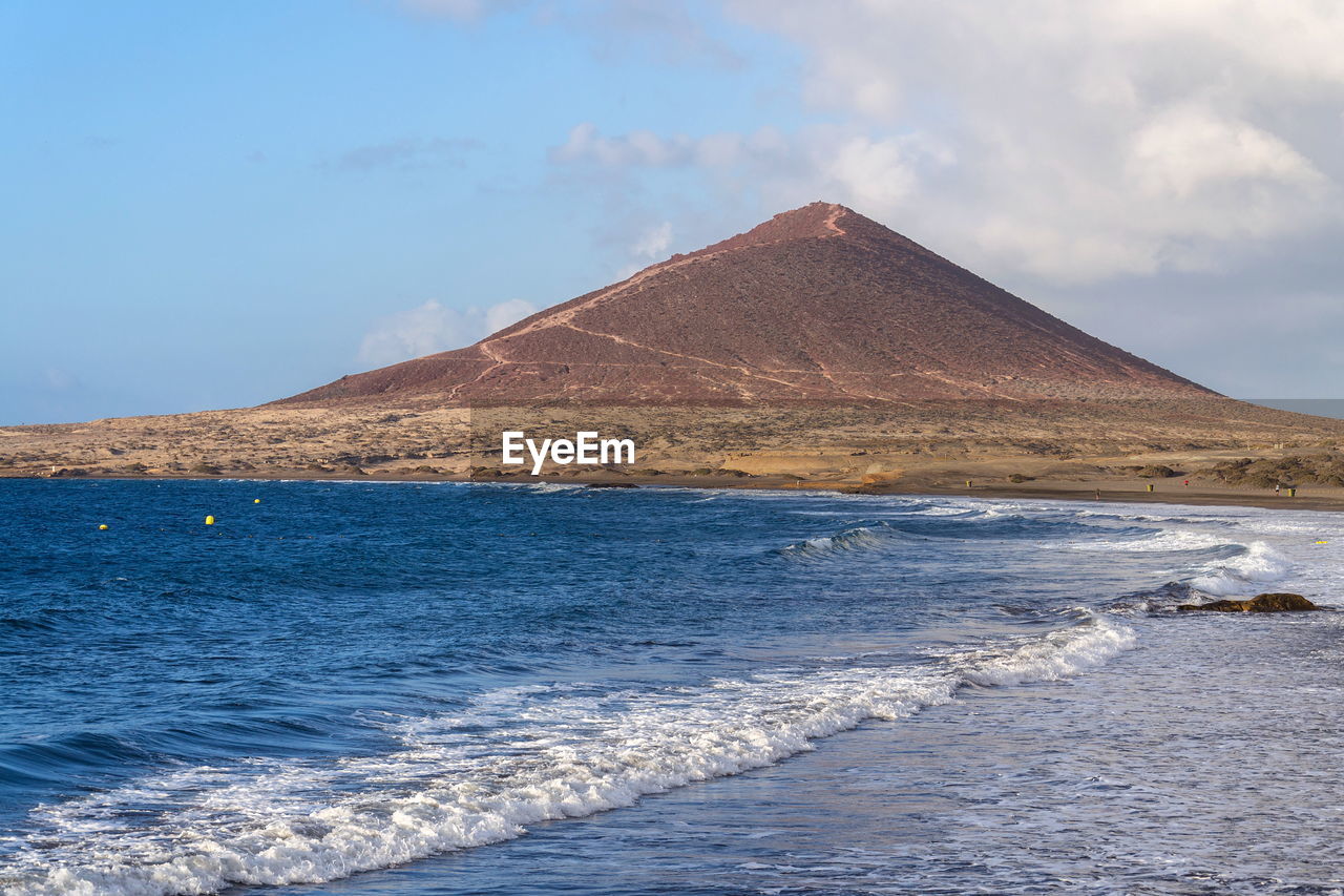 sea, water, land, sky, scenics - nature, travel destinations, nature, beauty in nature, coast, mountain, cloud, ocean, horizon, environment, no people, travel, landscape, shore, beach, tourism, architecture, outdoors, day, volcano, non-urban scene, blue, body of water, tranquil scene, tranquility, sand