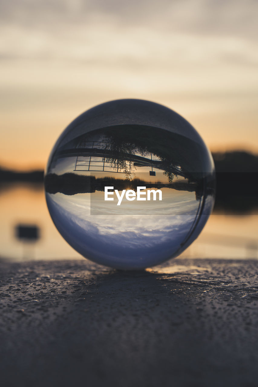 CLOSE-UP OF CRYSTAL BALL ON GLASS AGAINST SUNSET SKY