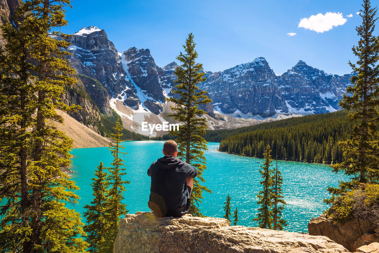 rear view of man standing by lake against sky