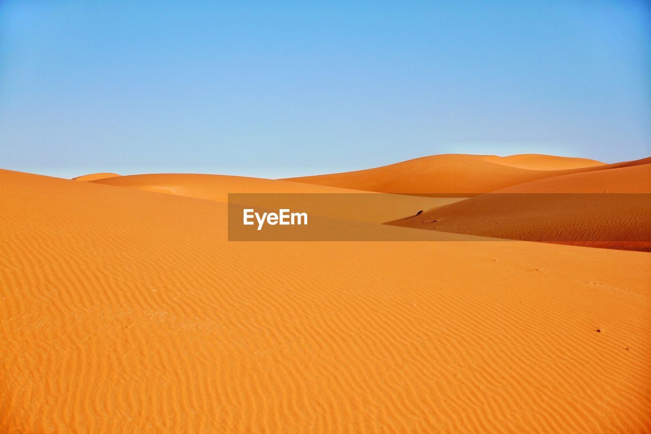 SAND DUNES IN DESERT AGAINST CLEAR SKY