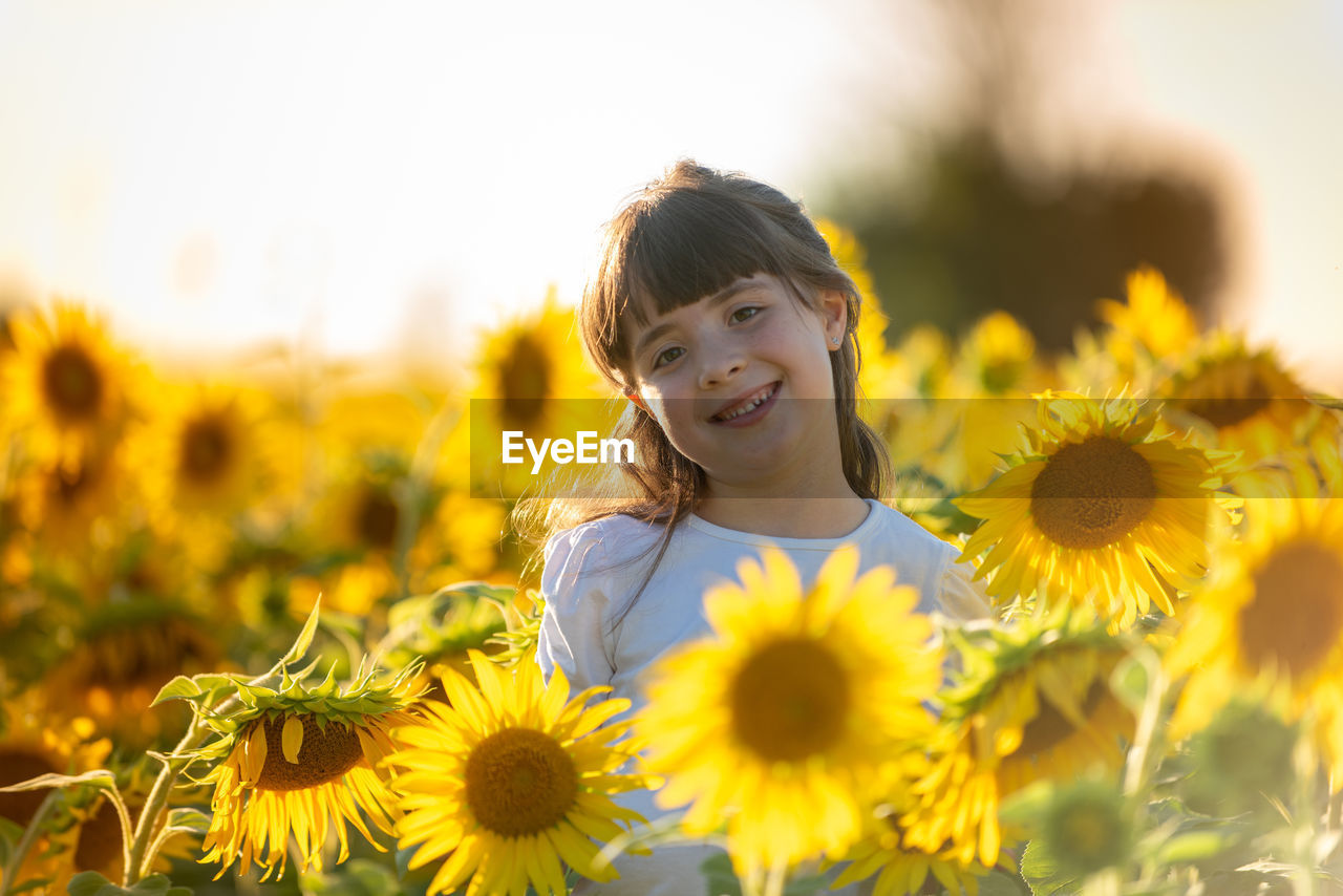 PORTRAIT OF GIRL ON YELLOW FLOWERING PLANTS