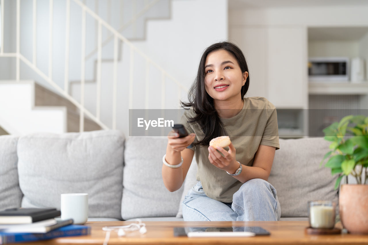 portrait of young woman using mobile phone while sitting on table