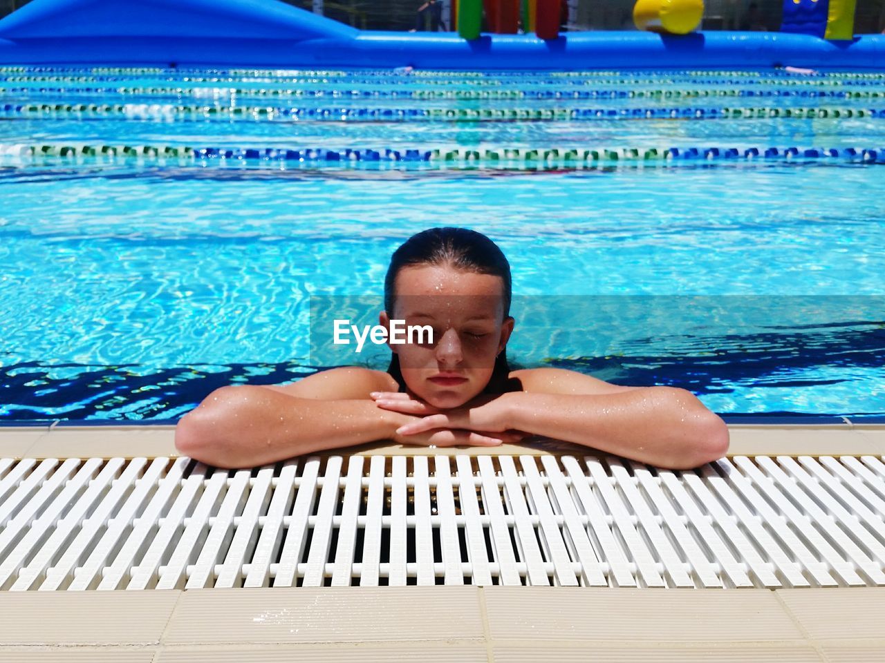 Young woman with eyes closed relaxing at poolside during sunny day