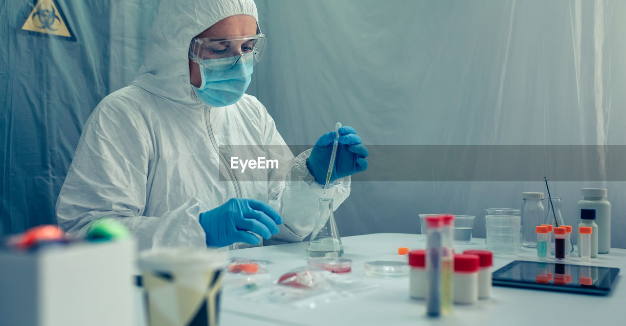 Scientist in protective suit working over chemical at laboratory