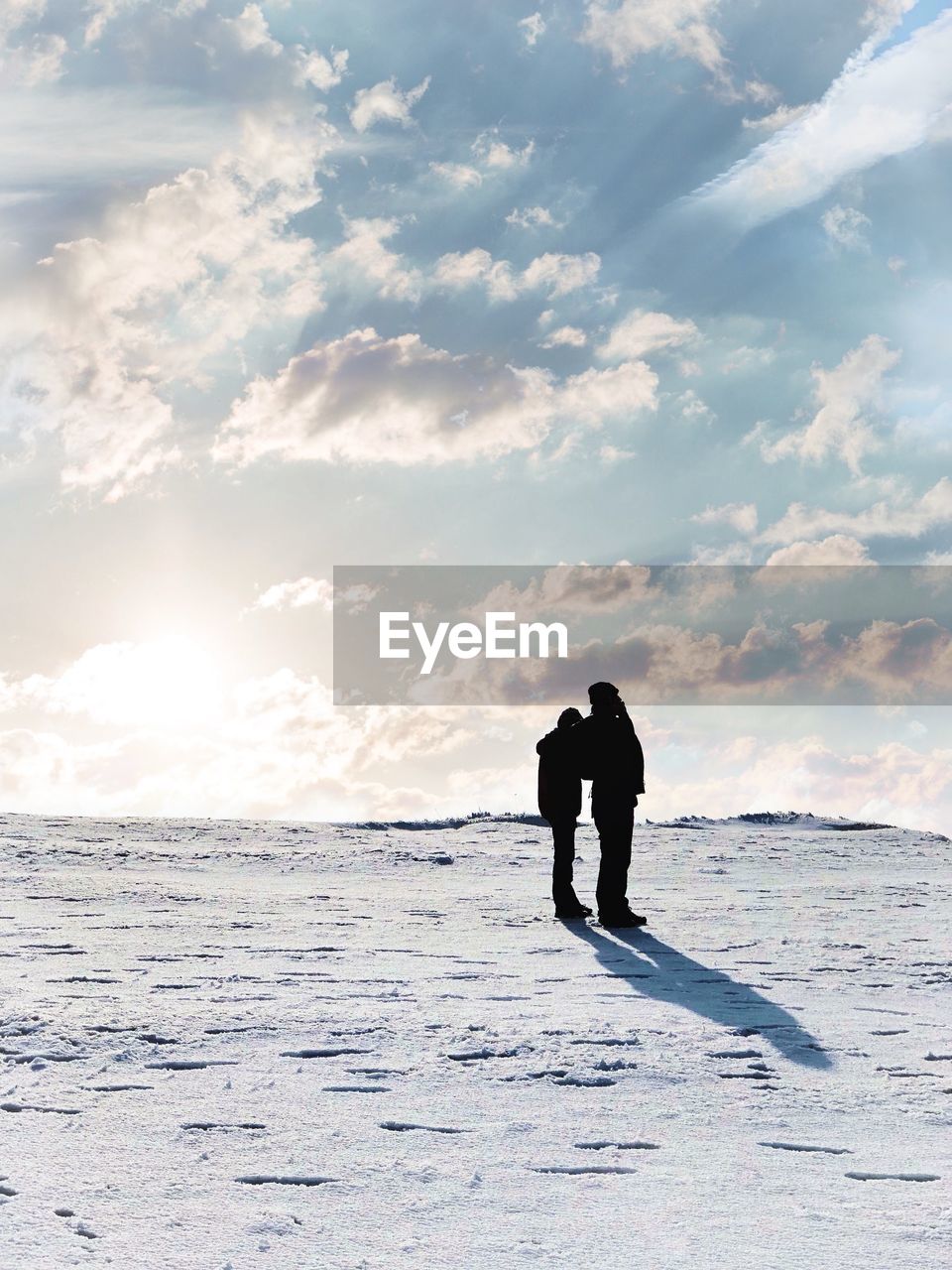 SILHOUETTE MAN STANDING ON SHORE AGAINST SKY DURING WINTER