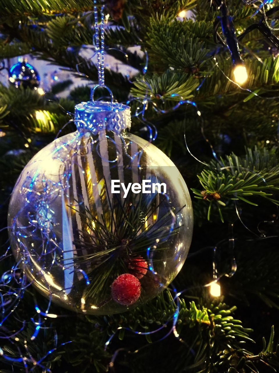 Close-up of silver bauble hanging on illuminated christmas tree