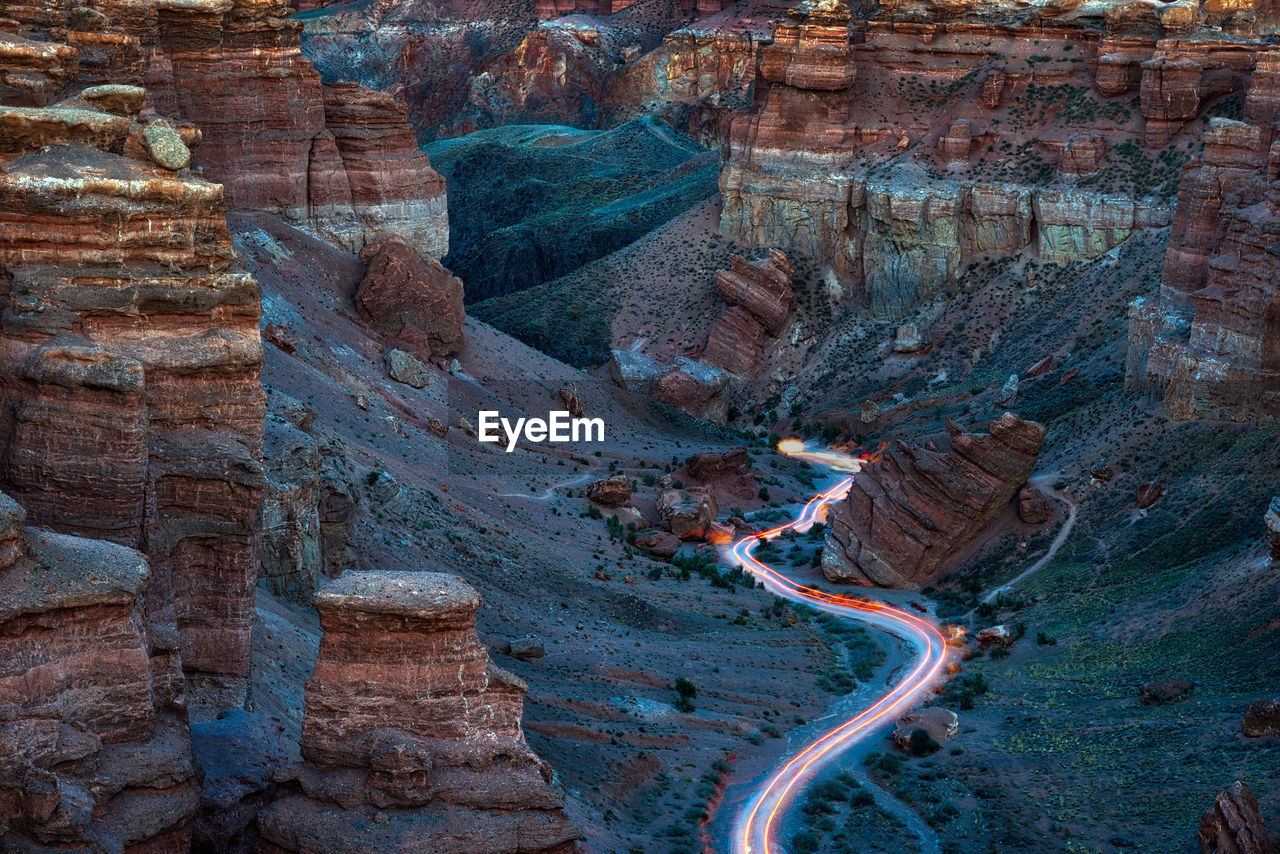 Aerial view of light trails on road amidst rock formations in desert