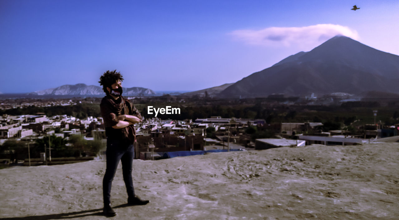 MAN STANDING ON MOUNTAIN AGAINST SKY