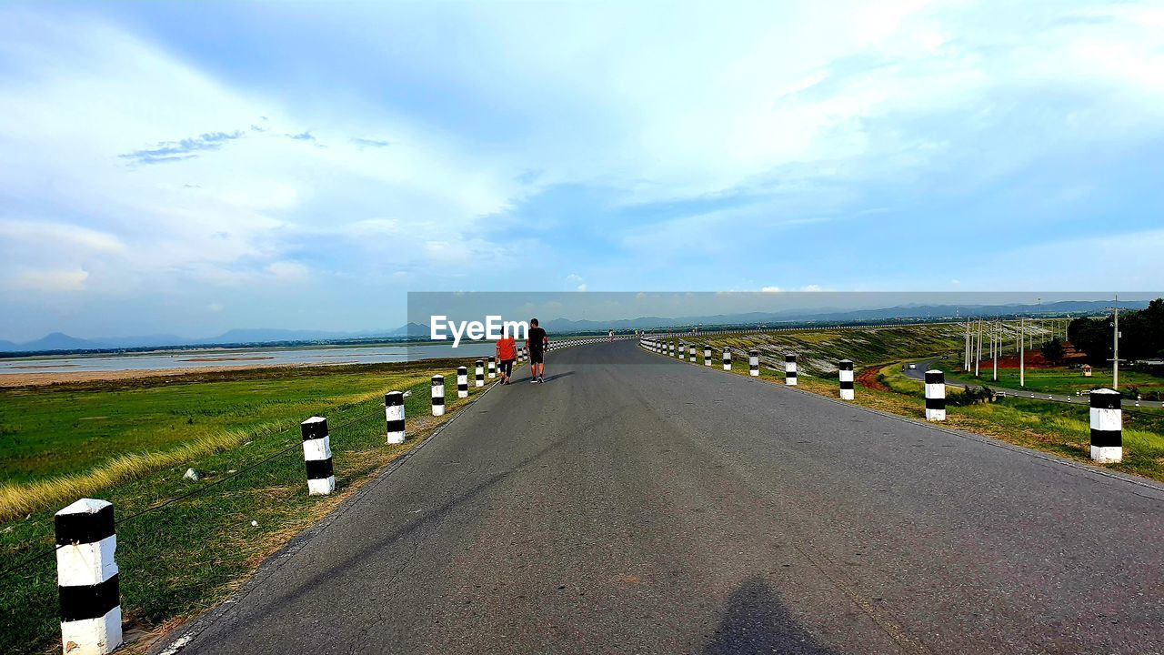 PEOPLE ON ROAD AGAINST SKY