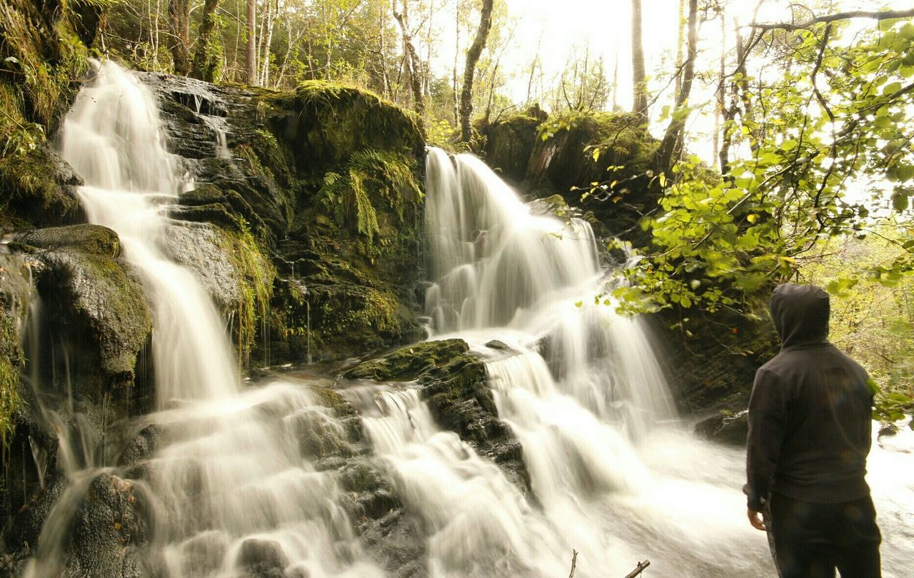 Man standing against waterfall