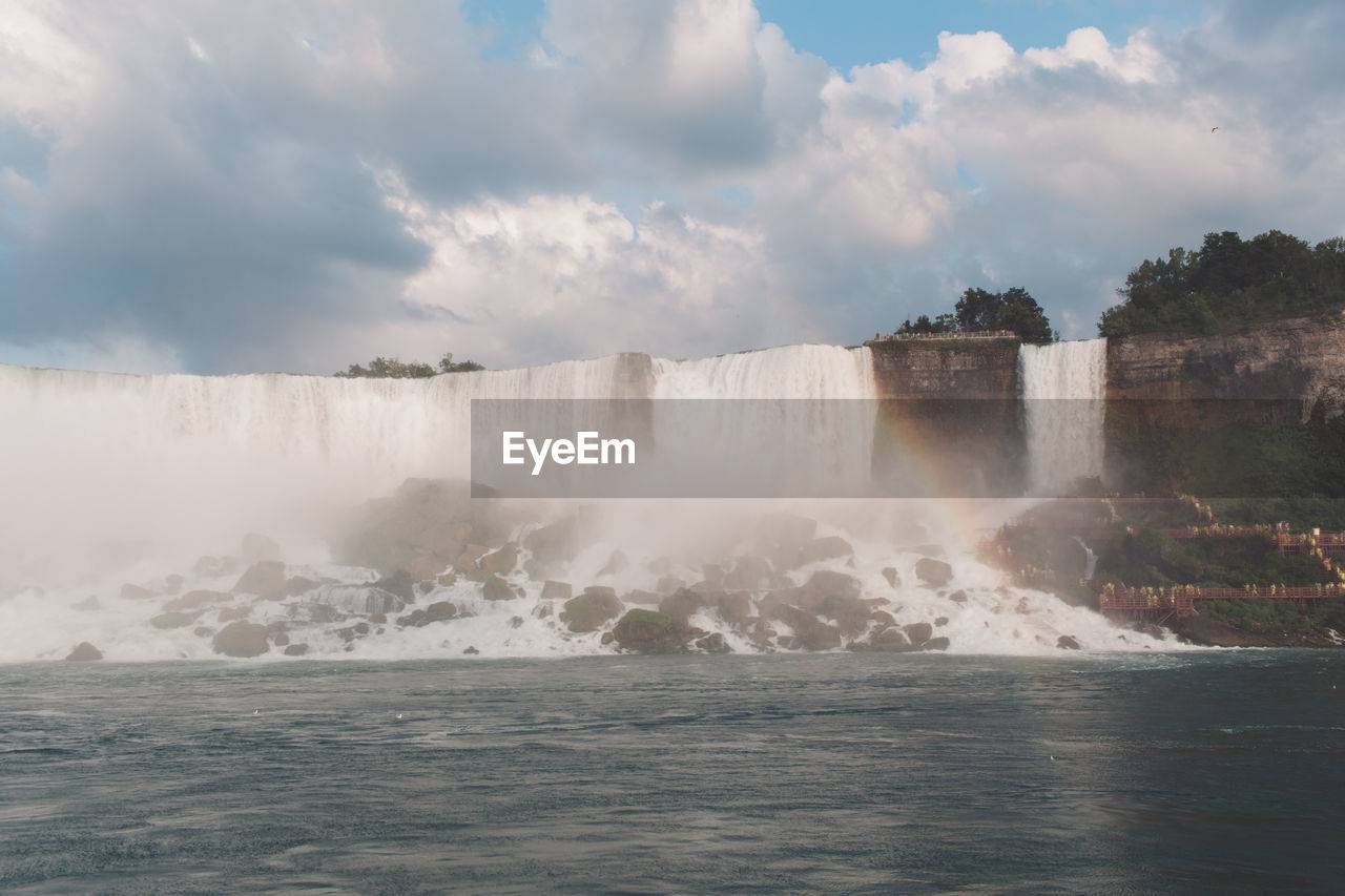 Scenic view of rainbow against waterfall