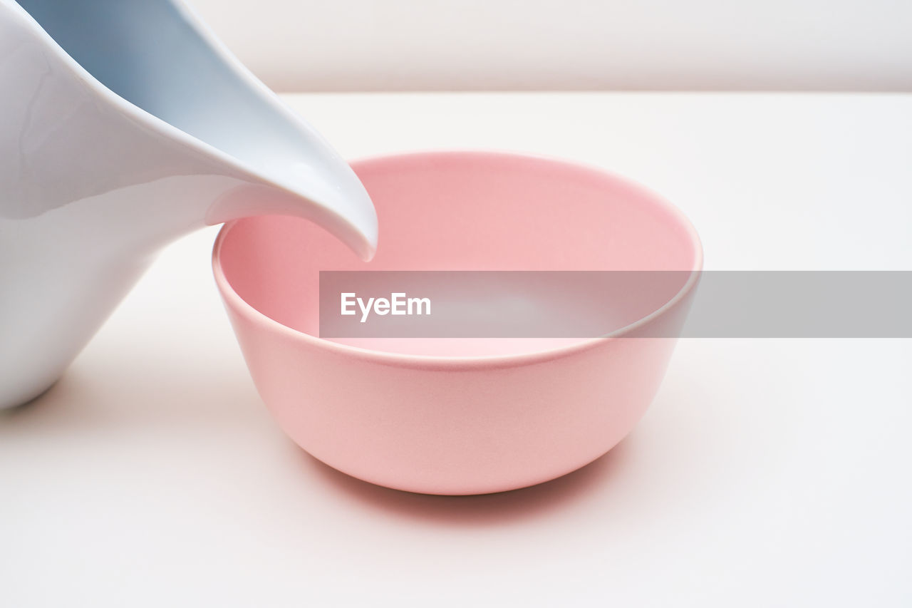 A pink bowl and a white carafe on a table