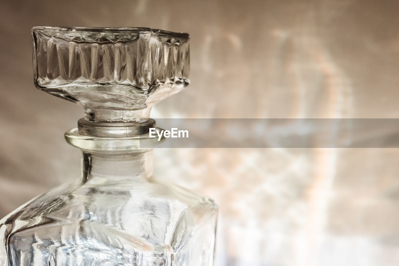 CLOSE-UP OF GLASS BOTTLES ON TABLE AGAINST WALL