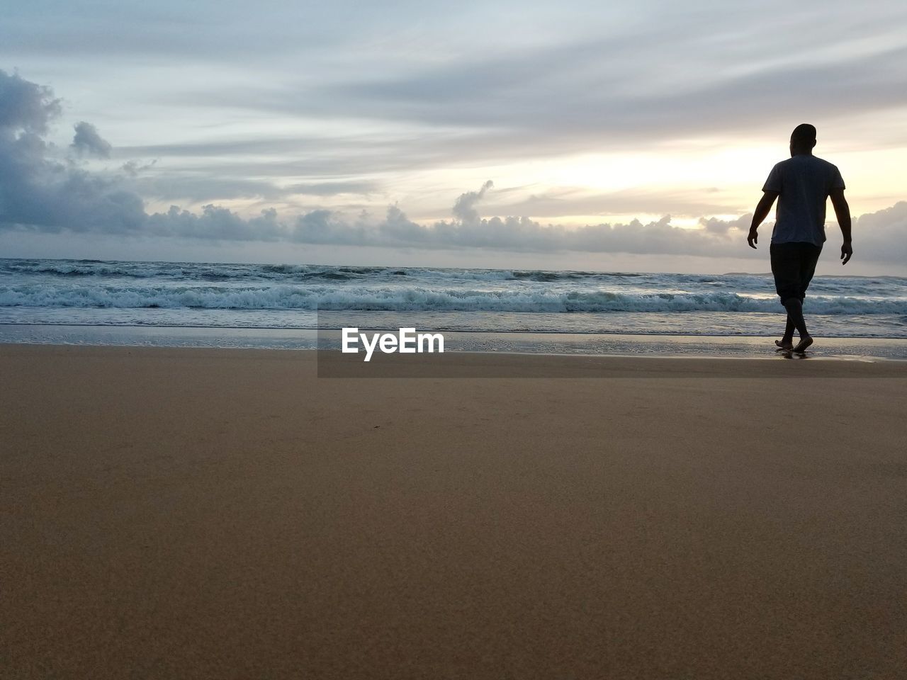 Full length of man walking on shore at beach against sky