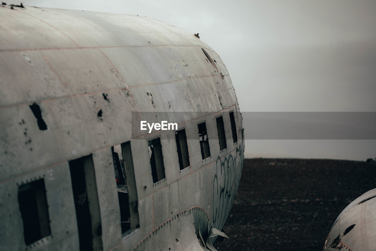 Abandoned airplane on beach against sky