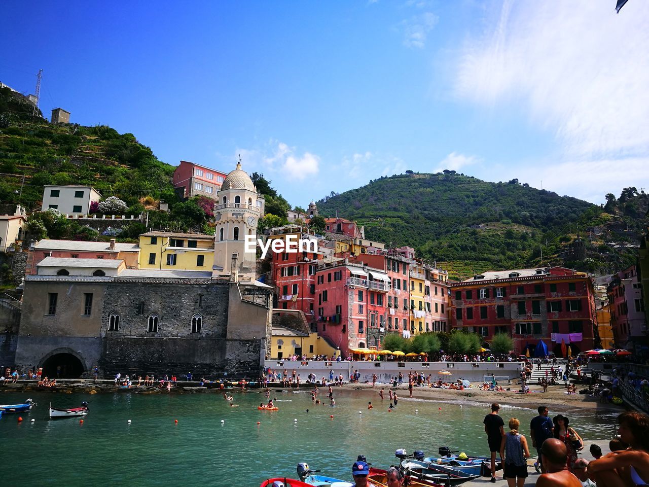 GROUP OF PEOPLE ON BOATS AGAINST BUILDINGS AND MOUNTAIN