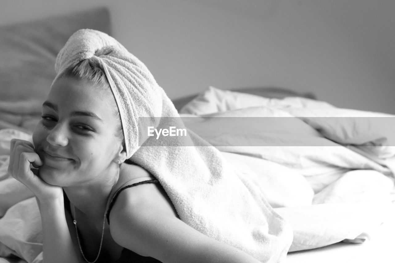 Portrait of young woman relaxing on bed at home