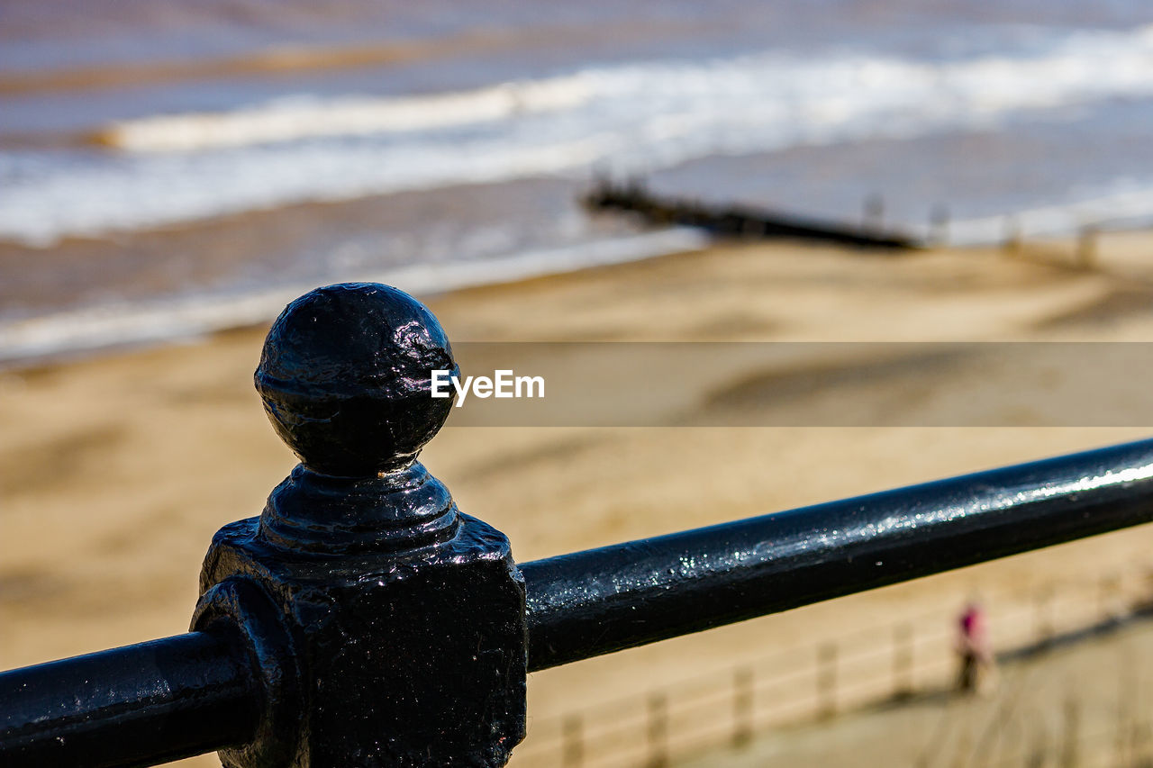 CLOSE-UP OF METAL RAILING ON SHORE