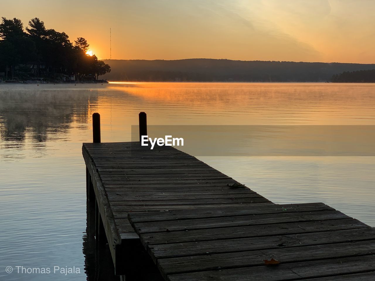 Pier on lake against sky during sunset