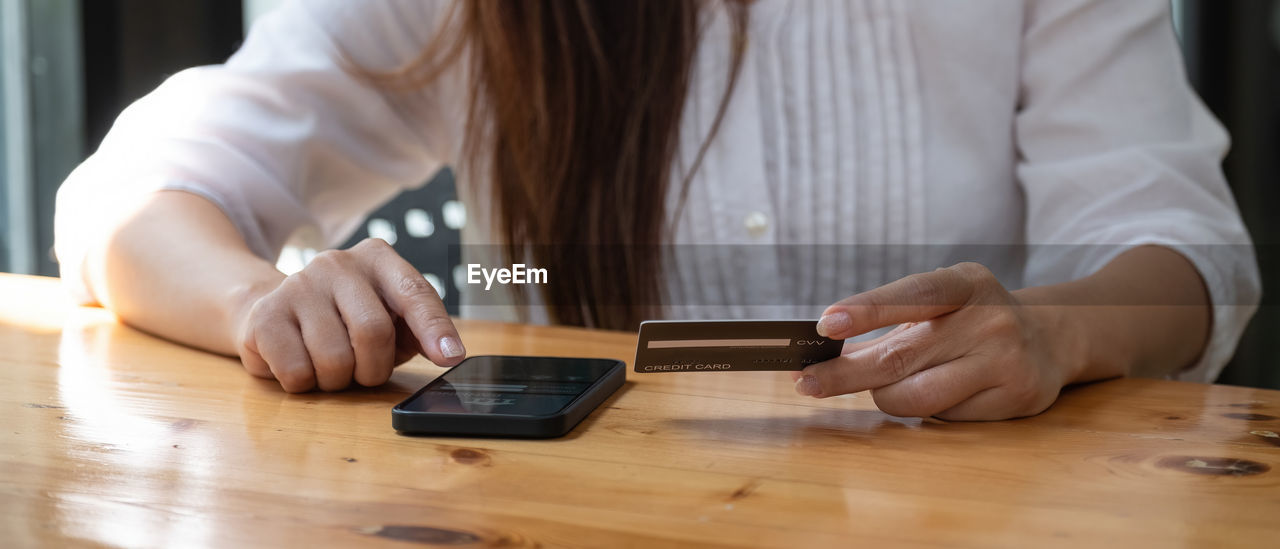 Midsection of woman using smart phone on table