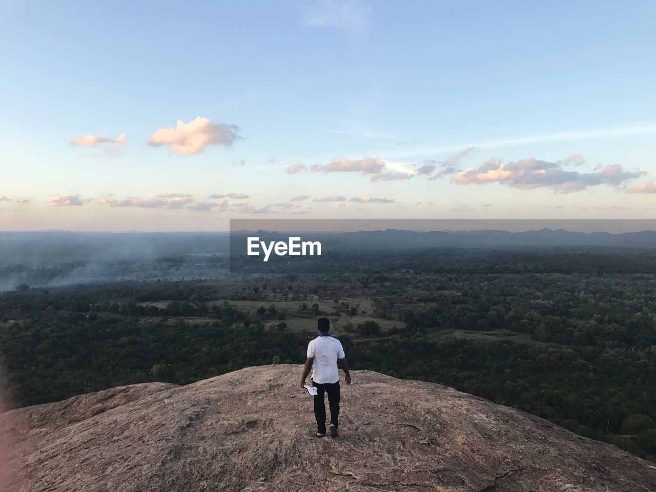 Rear view of man standing on mountain against sky