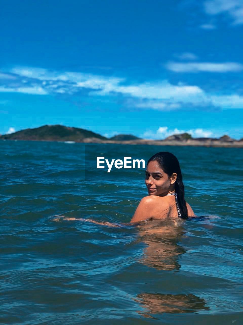 Portrait of woman swimming in sea against blue sky