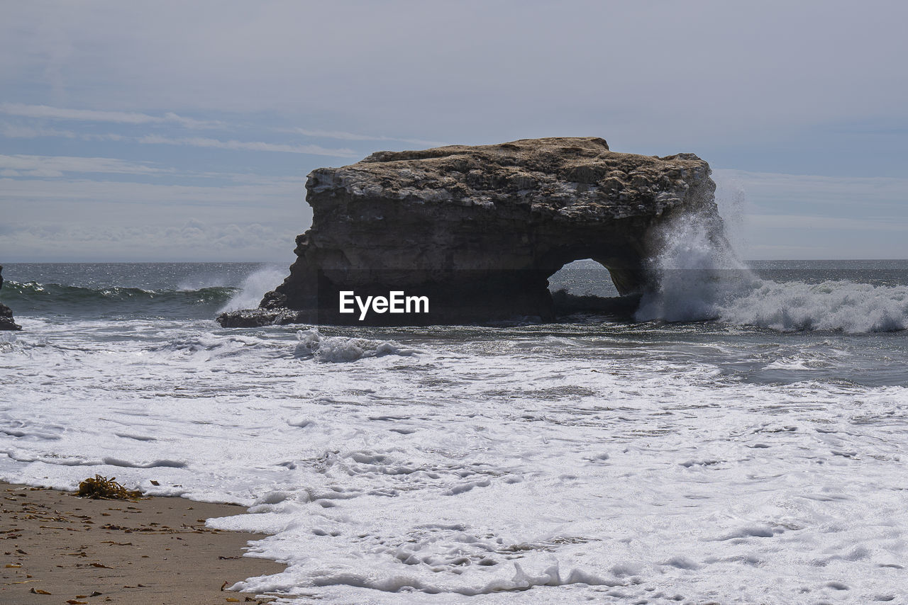 Rock formation on sea shore against sky