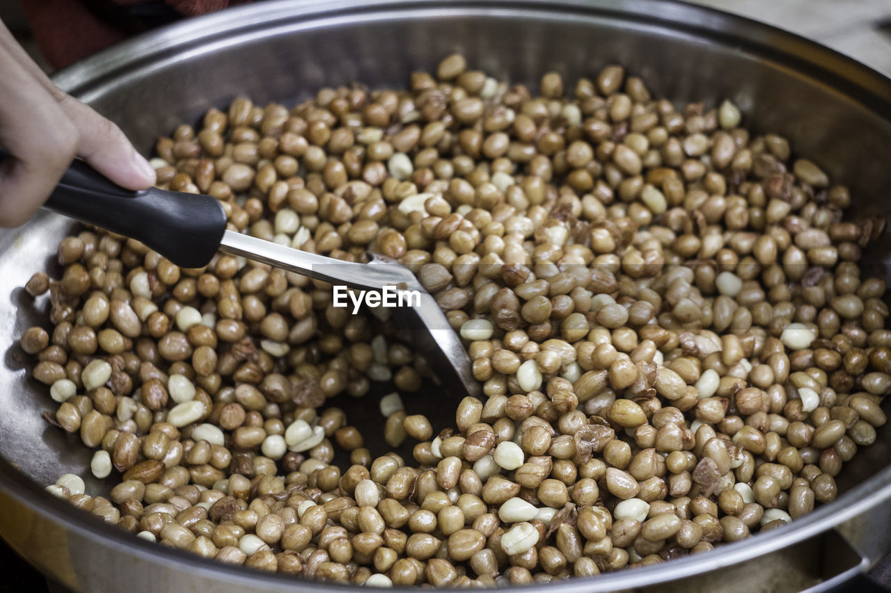 Close-up of person stirring peanuts in pan