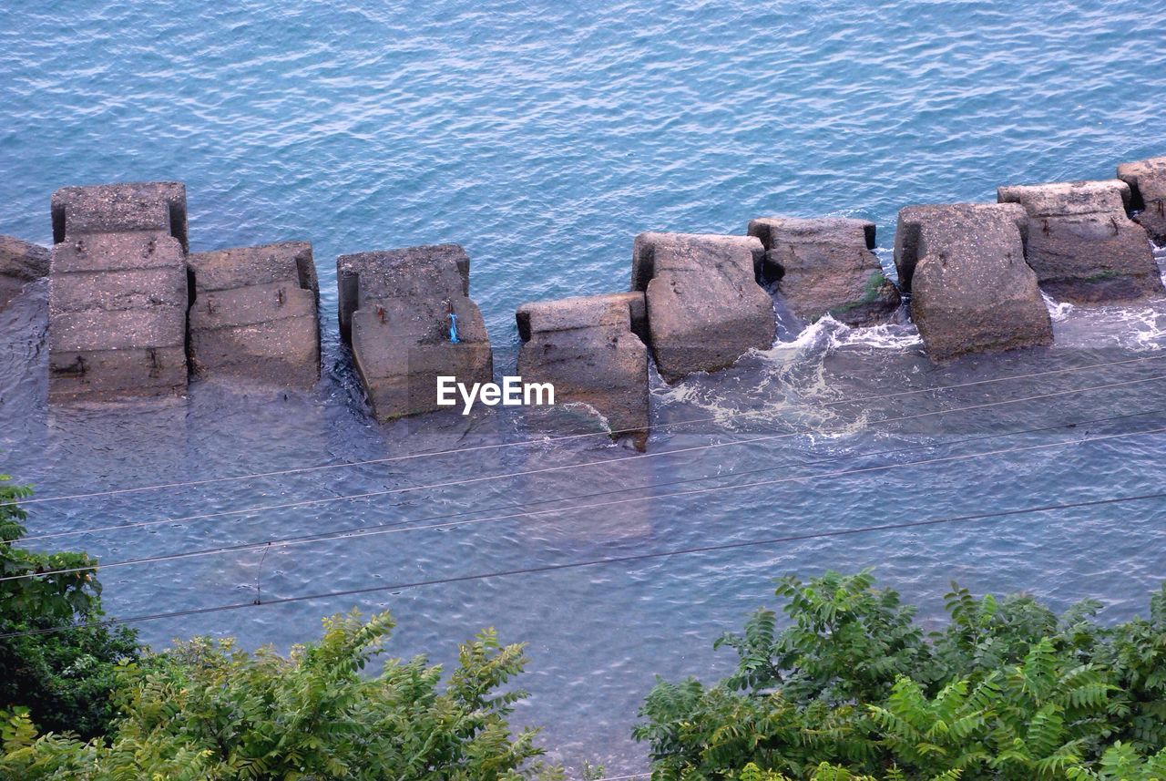 HIGH ANGLE VIEW OF ROCKS BY SEA