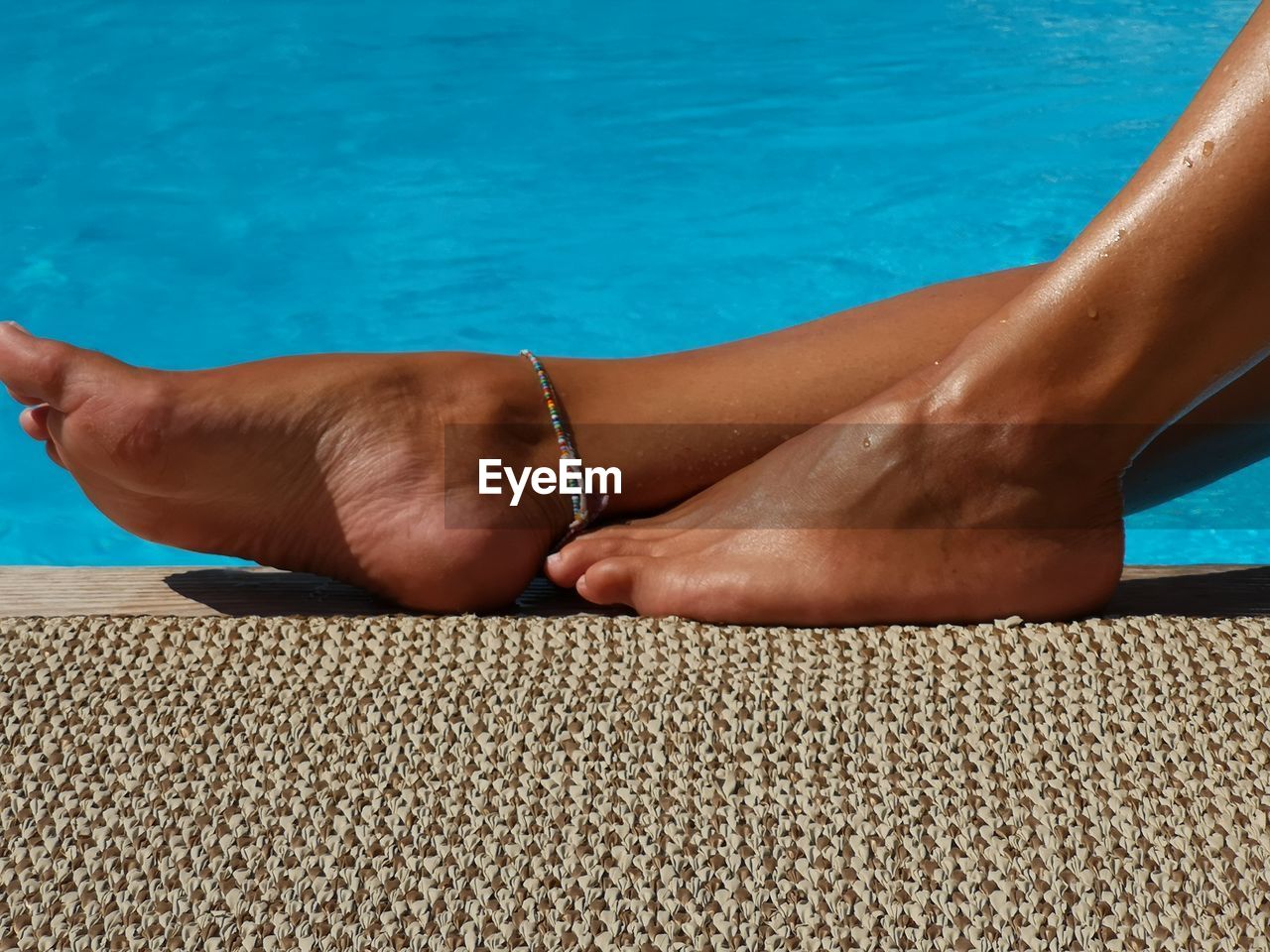 Low section of woman relaxing by poolside