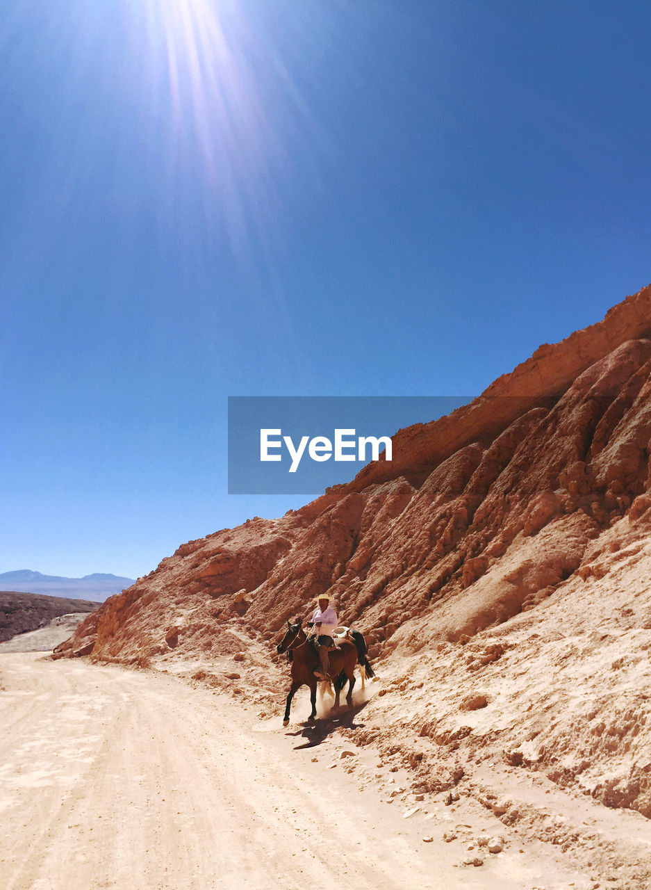 Man riding horse at atacama desert on sunny day