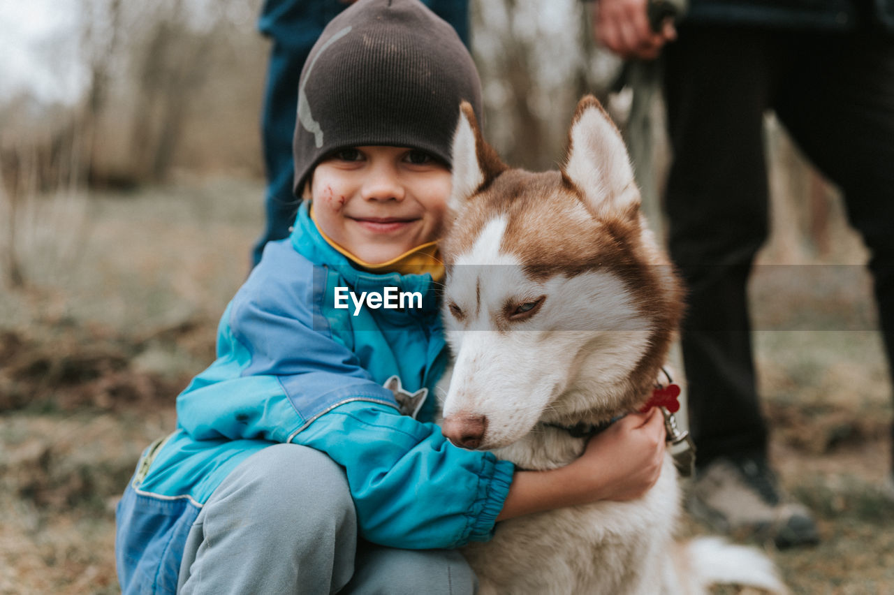 Kid and his friend husky siberian dog. portrait little child boy hugging cute white brown animal pet