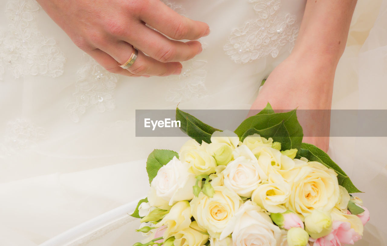 Mid section of a bride holding bouquet