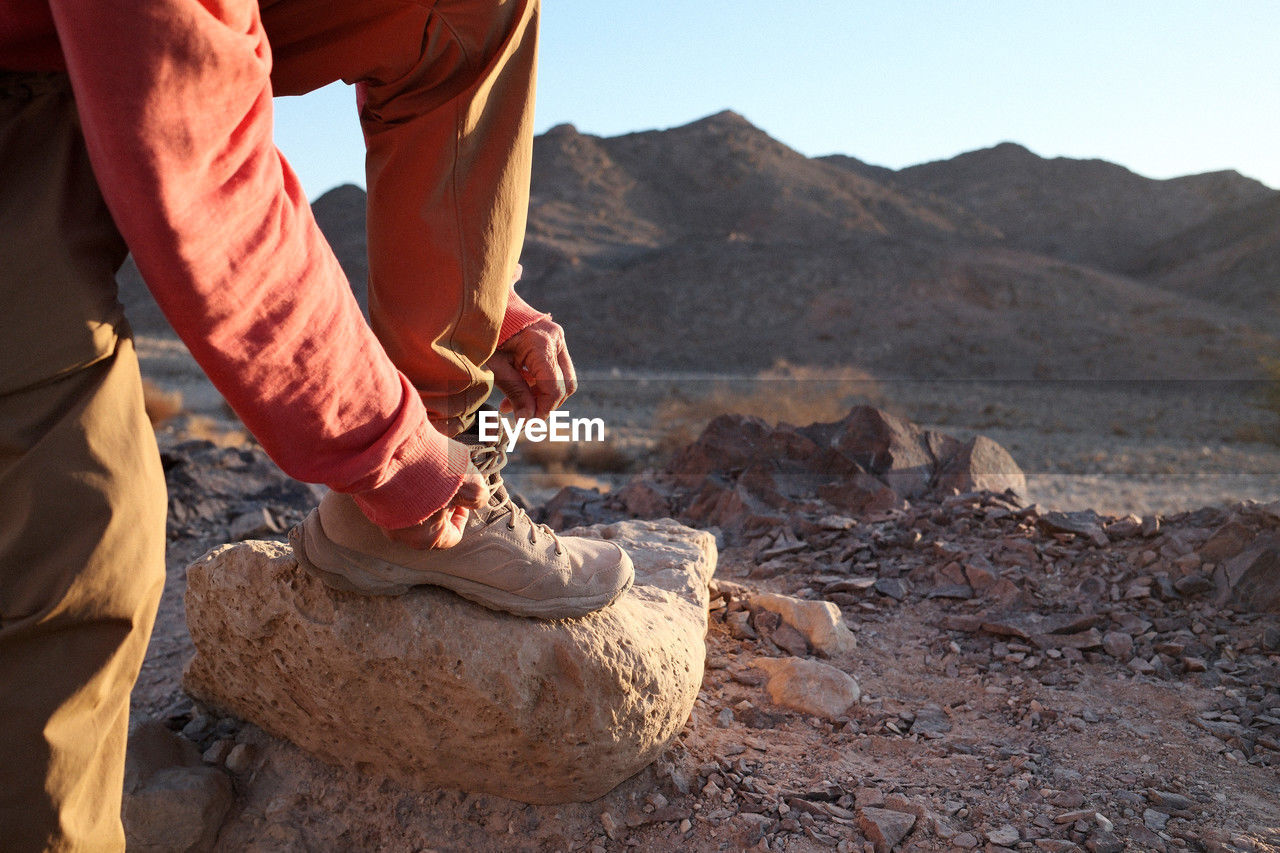 one person, adult, nature, geology, men, rock, landscape, mountain, environment, soil, land, day, hiking, sky, leisure activity, outdoors, travel, activity, travel destinations, occupation, adventure, sunlight, scenics - nature, lifestyles, sand, human leg