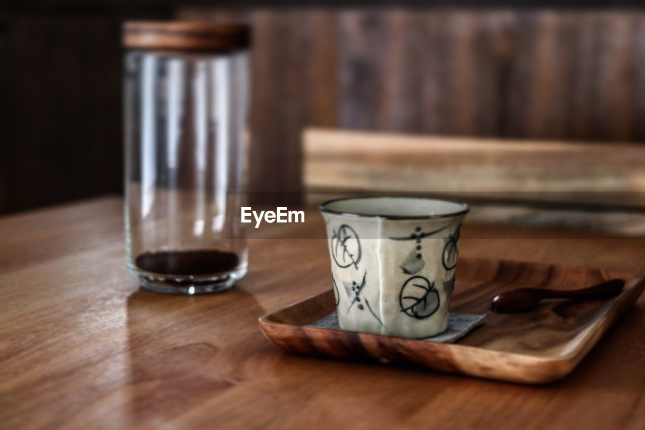 CLOSE-UP OF COFFEE CUP AND SPOON ON TABLE