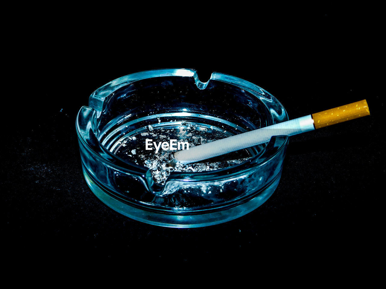 Close-up of burnt cigarette in ashtray on black background