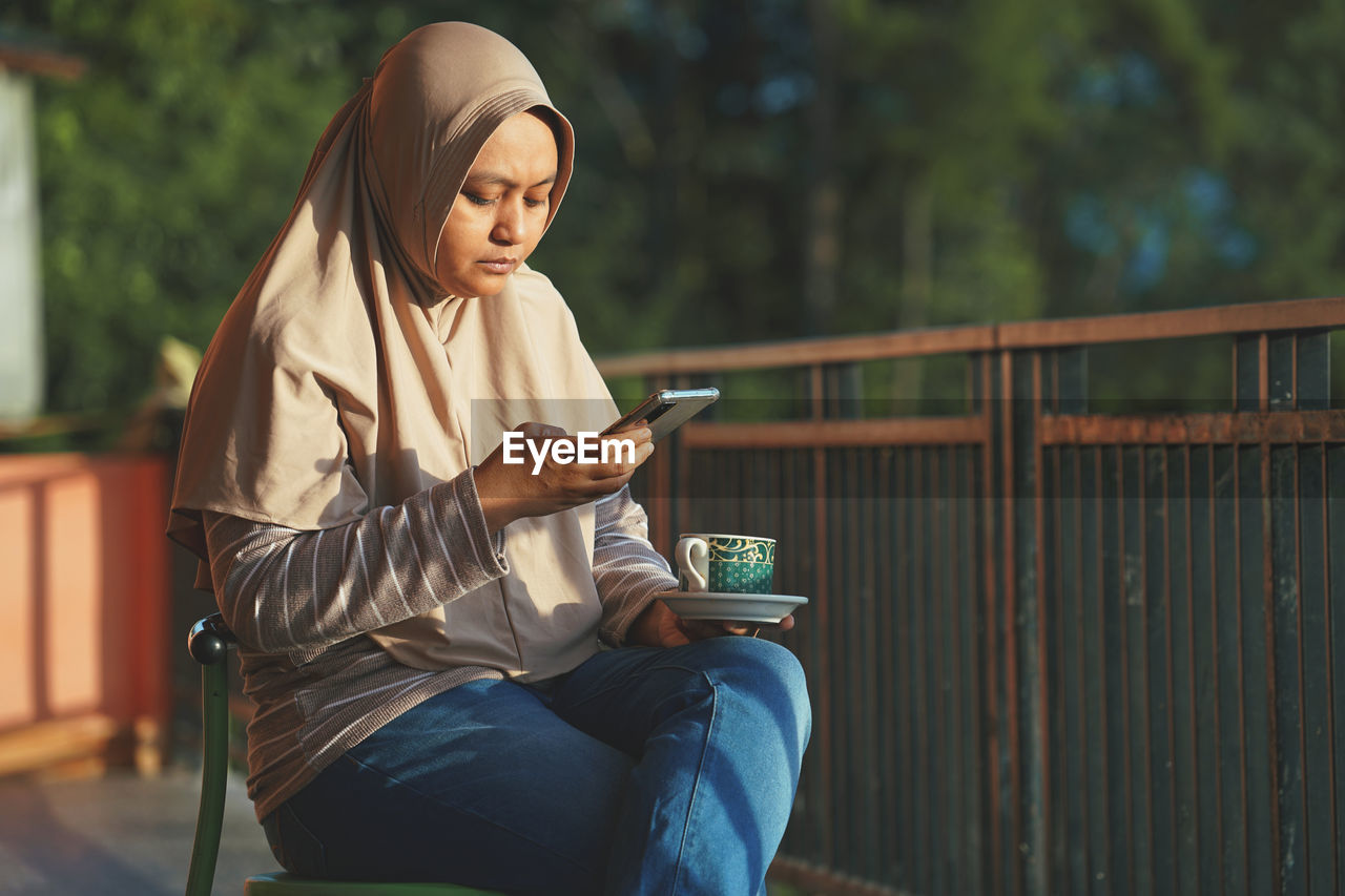 Muslim woman sitting enjoying tea in the sun