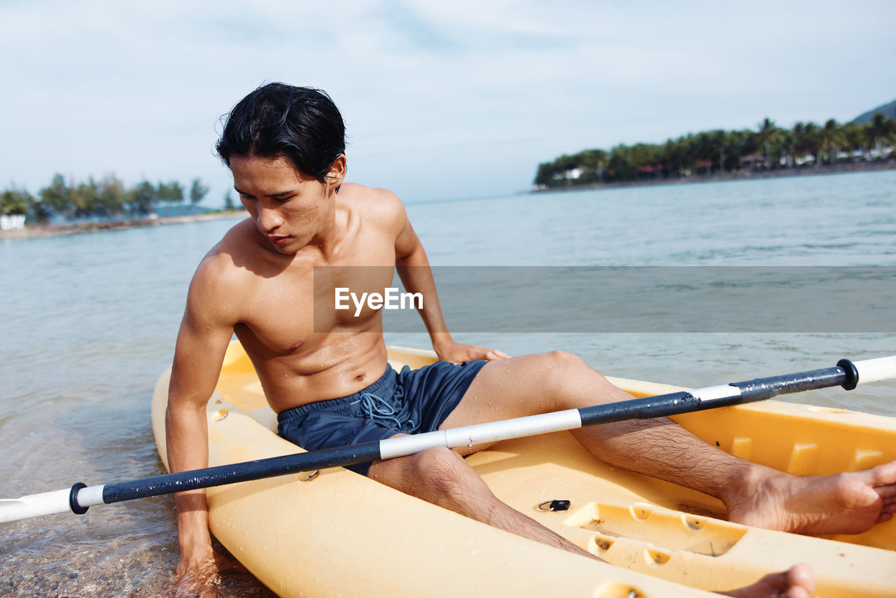 portrait of shirtless man sitting in boat