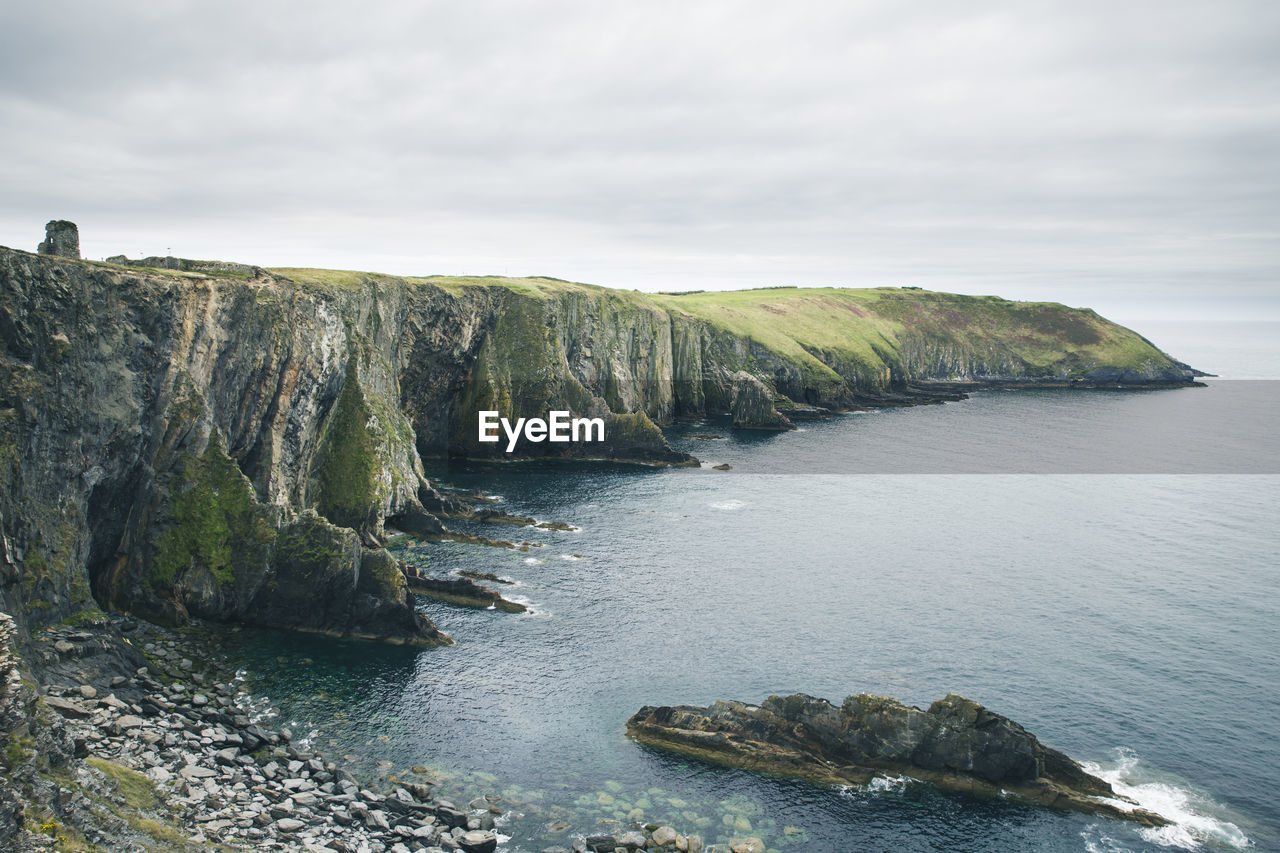 Scenic view of sea by cliff against sky