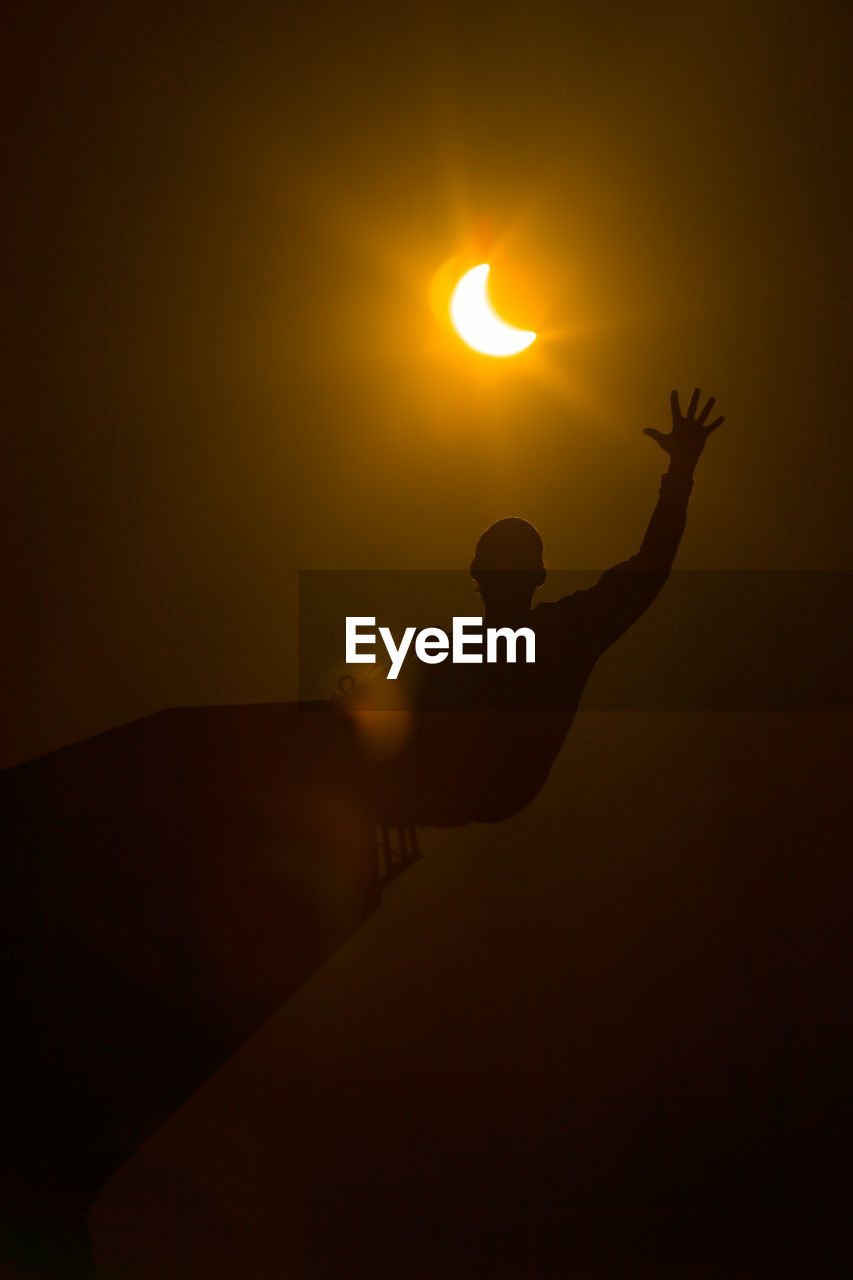 Low angle view of silhouette man with arms raised against sky